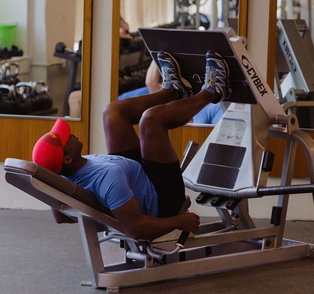 A gym member works out on a Cybex leg press machine in the natural light-filled strength training area at MINT gym in Adams Morgan, Washington DC